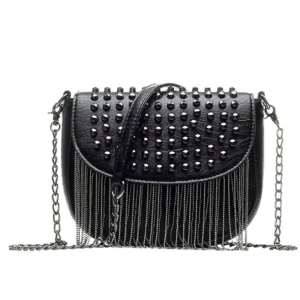 Gothic studded leather shoulder bag worn as crossbody style, three-quarter view displaying chain tassel and rivet embellishments