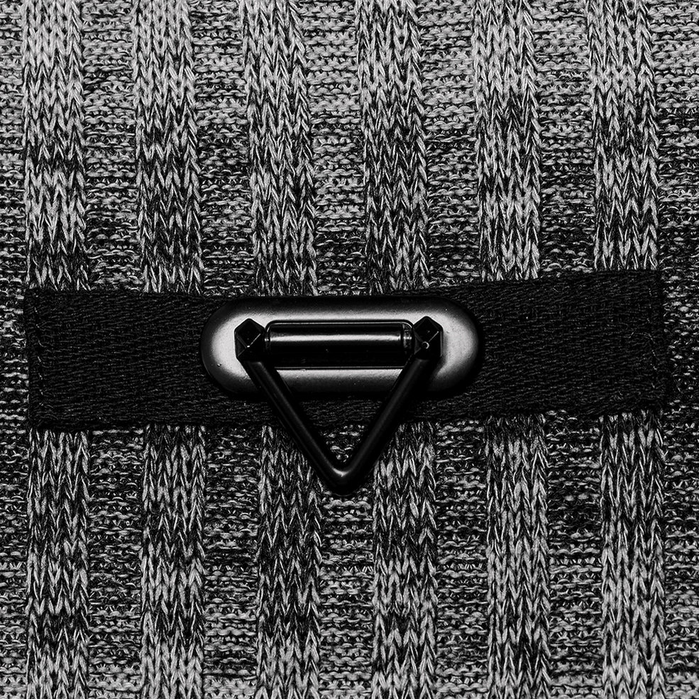 Close-up detail shot of metal triangle buckle trim at sweater collar on monochrome striped gothic knit fabric
