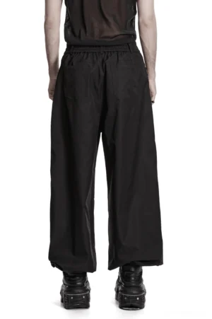 Black techwear gothic pants rear full view showcasing wide leg silhouette, elasticated waistband, and architectural back design