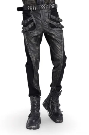 Men's black gothic techwear pants with distressed leather panels and adjustable buckle straps, full-body front view on male model