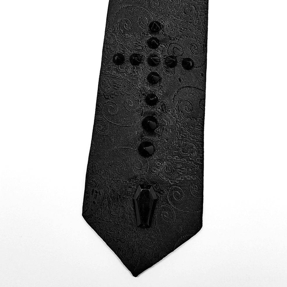 Close-up flat lay of gothic necktie blade detail featuring round studs, coffin charm, and detailed jacquard pattern texture