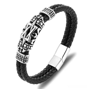 Black braided genuine leather gothic totem bracelet for men with silver-toned carved ornament and magnetic clasp, front flat lay view on wooden surface