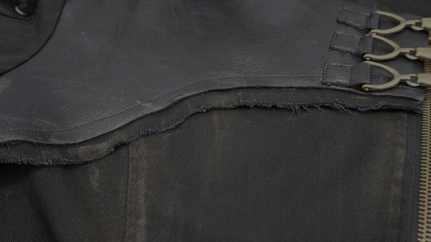 Shoulder seam and hardware detail of gothic hooded trench coat with stitched leather panel and zipper trim