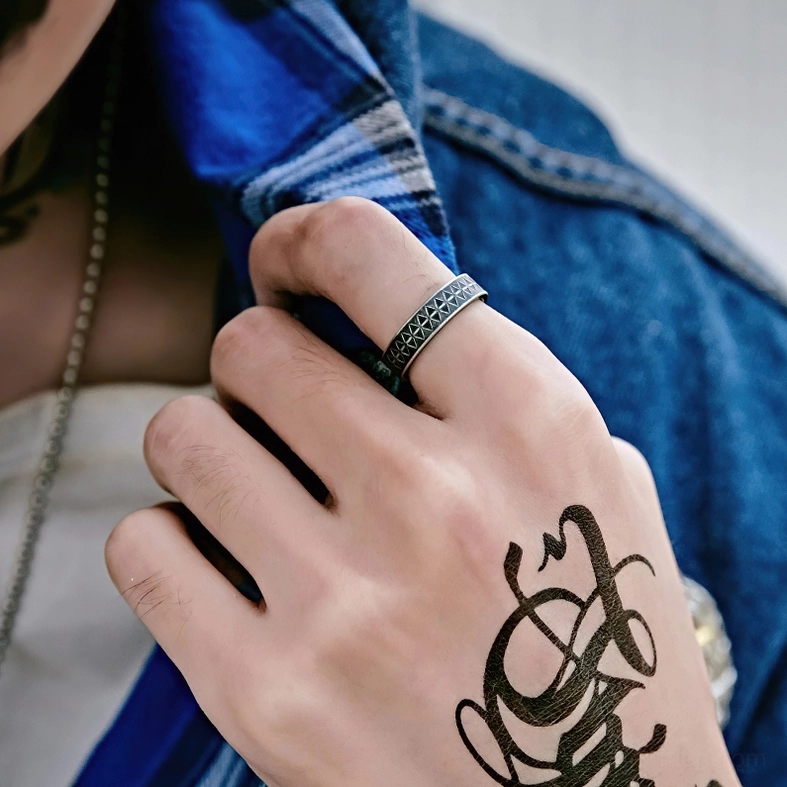 Man wearing gothic stainless steel triangle ring on index finger tattooed hand side close-up