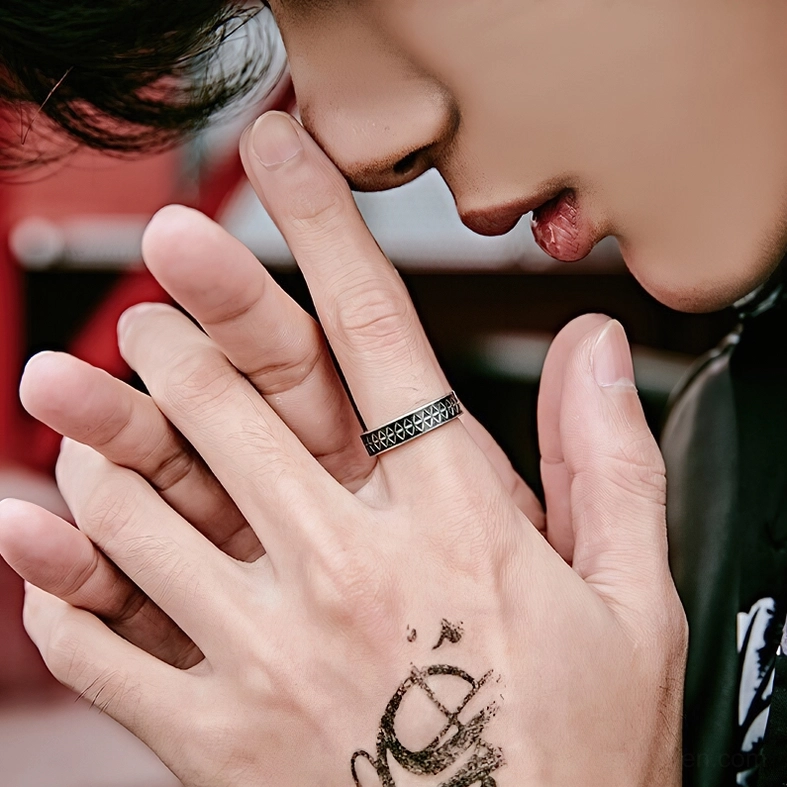 Male model styled in gothic stainless steel triangle ring frontal hand shot casual indoor setting