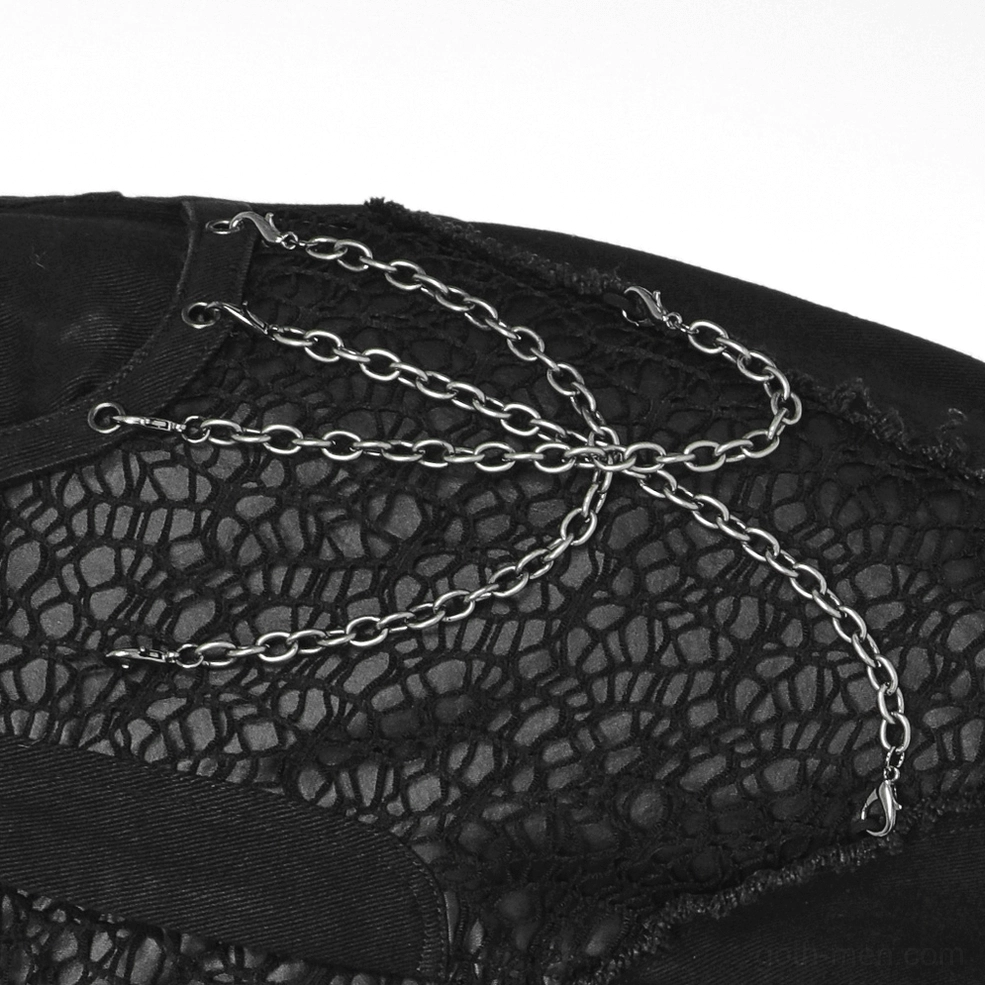 Close-up of decorative metal chains and spiderweb lace panel on gothic trousers knee area