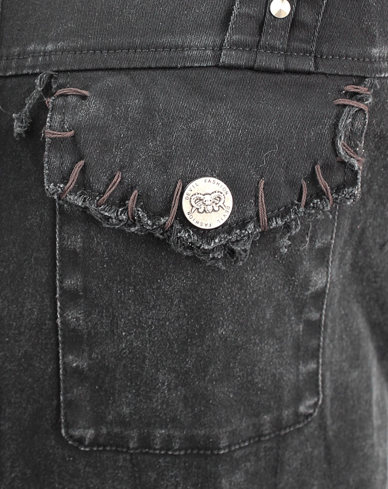 Close-up of black gothic vest chest pocket with metal button and frayed stitched edge
