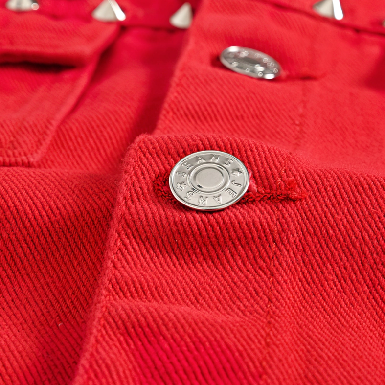 Close-up of embossed branded metal snap buttons on red denim gothic vest