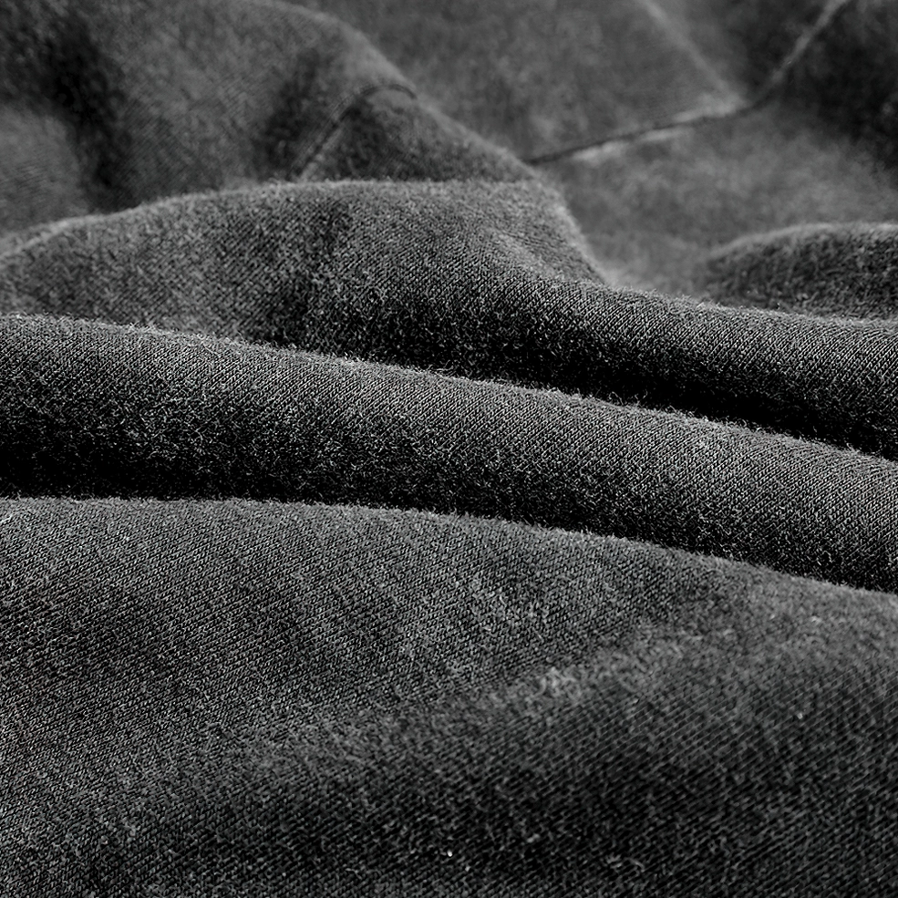 Close-up texture detail of washed black cotton fabric of gothic corset vest, showing matte surface and weathered distressed finish
