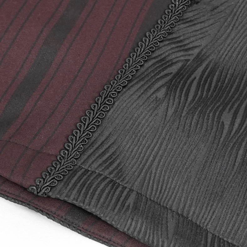Close-up of ornate braided decorative trim and edge detail on gothic waistcoat showing textured black panel and striped fabric