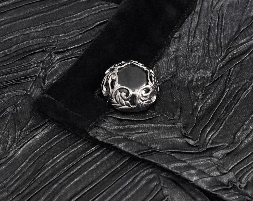 Ornate engraved metal button close-up of black gothic waistcoat with velvet binding and craftsmanship detail