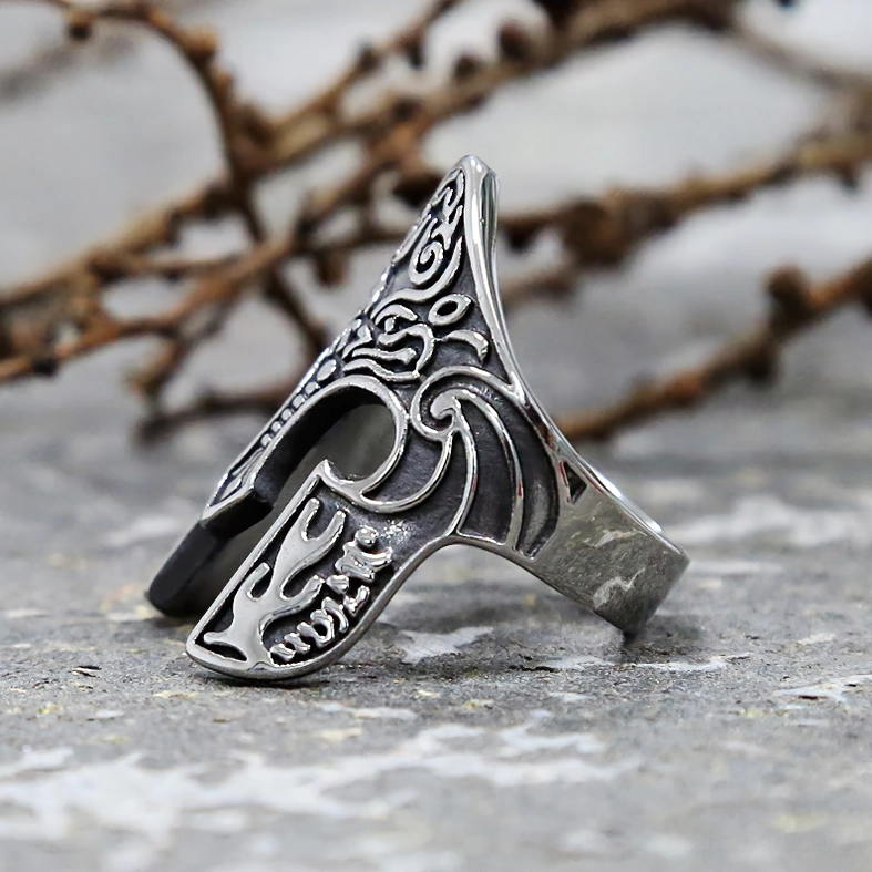 Antique silver gothic warrior helmet ring with embossed totem patterns on stone background