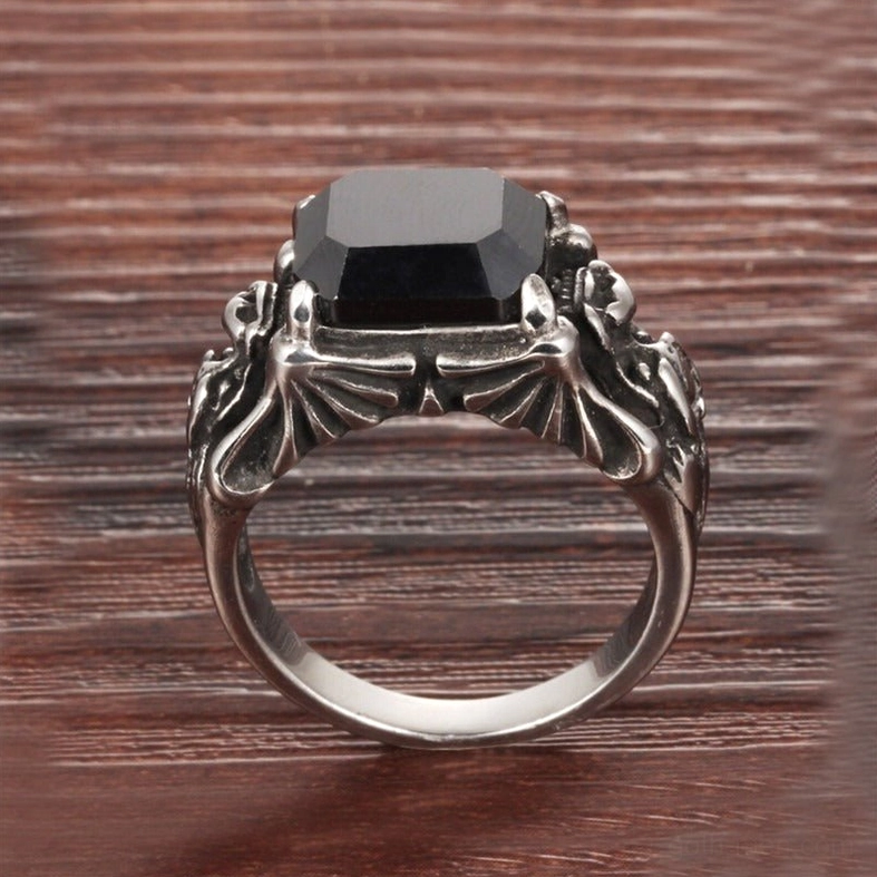 Winged retro engravings on polished silver gothic ring band with square black zircon stone, top front angle