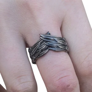 Dark gray gothic wings ring worn on finger, showing intricate feather carving detail and vintage dark metal finish from front view