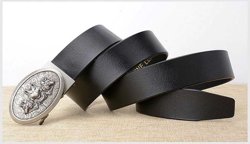 Multiple black cowhide gothic belts with silver wolf buckles, overlapped display on linen tabletop, collection shot