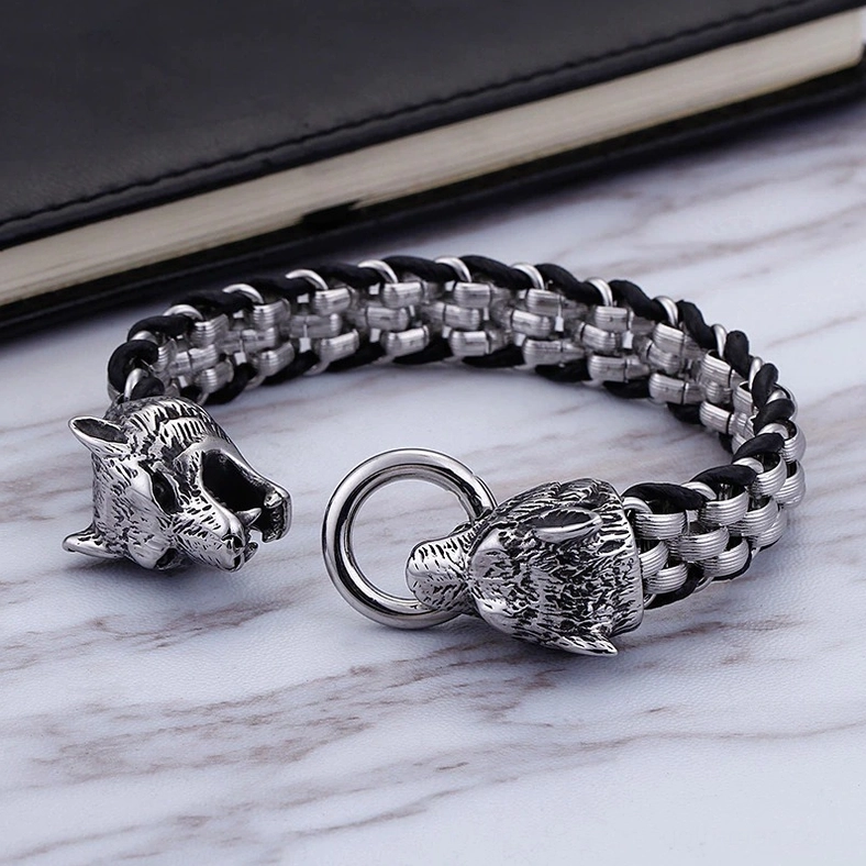 Detachable wolf head bracelet three-quarter view showing separated clasp and woven chain links with notebook prop