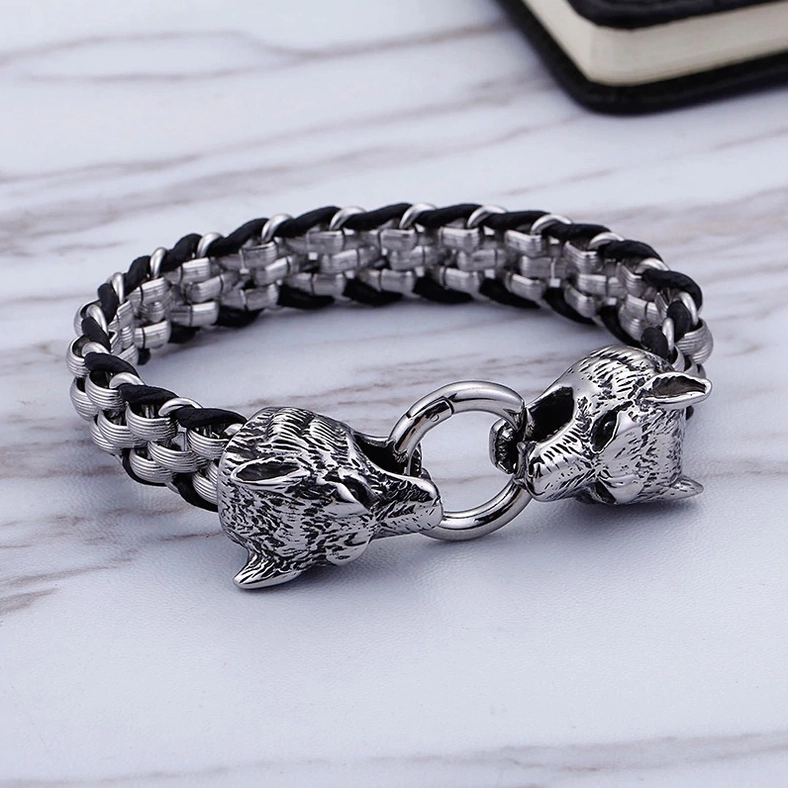 Black and silver wolf head bracelet overhead flat lay on marble surface showing full chain length and clasp design