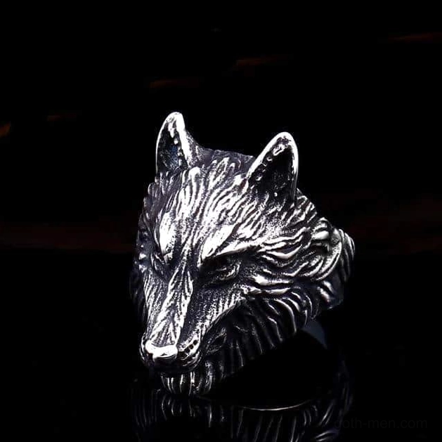 Realistic carved wolf head ring with detailed fur and solemn expression, antique silver finish, dark reflective background