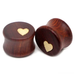 Close-up detail view of carved wooden heart design on ear tunnel stretcher showing natural wood grain and craftsmanship