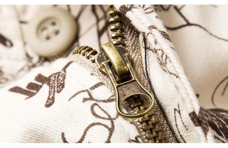 Metal zipper and button closure detail on graffiti printed gothic cargo shorts, top-down technical view
