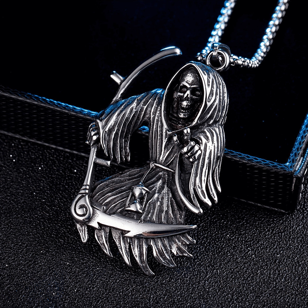 Aged silver tone stainless steel grim reaper scythe pendant dark blue jewelry background gothic alternative
