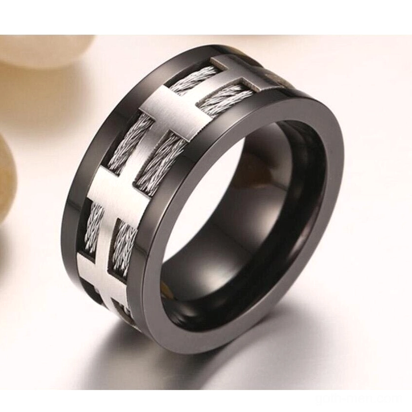 45-degree angle view of gun-black stainless steel gothic ring with cross and braided design on light background