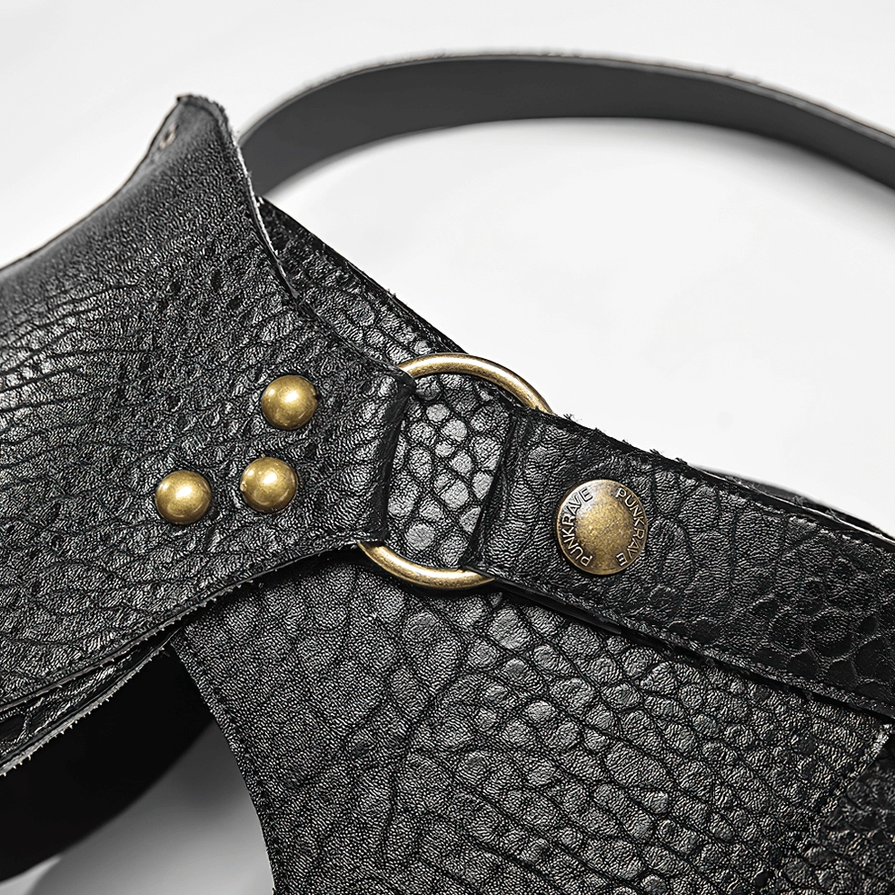 Macro close-up of gothic harness hardware showing bronze rivets, D-ring, and engraved metal buttons