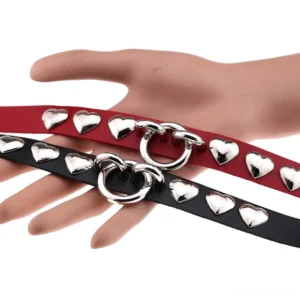 Multiple PU leather heart chokers in black and red displayed together showing O-ring and silver stud details, flat lay product photography