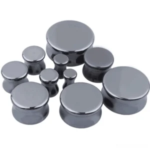 Flat lay collection of small hematite stone ear gauge set arranged in row, showing graduated sizes from 6mm to 25mm with polished gunmetal gray finish