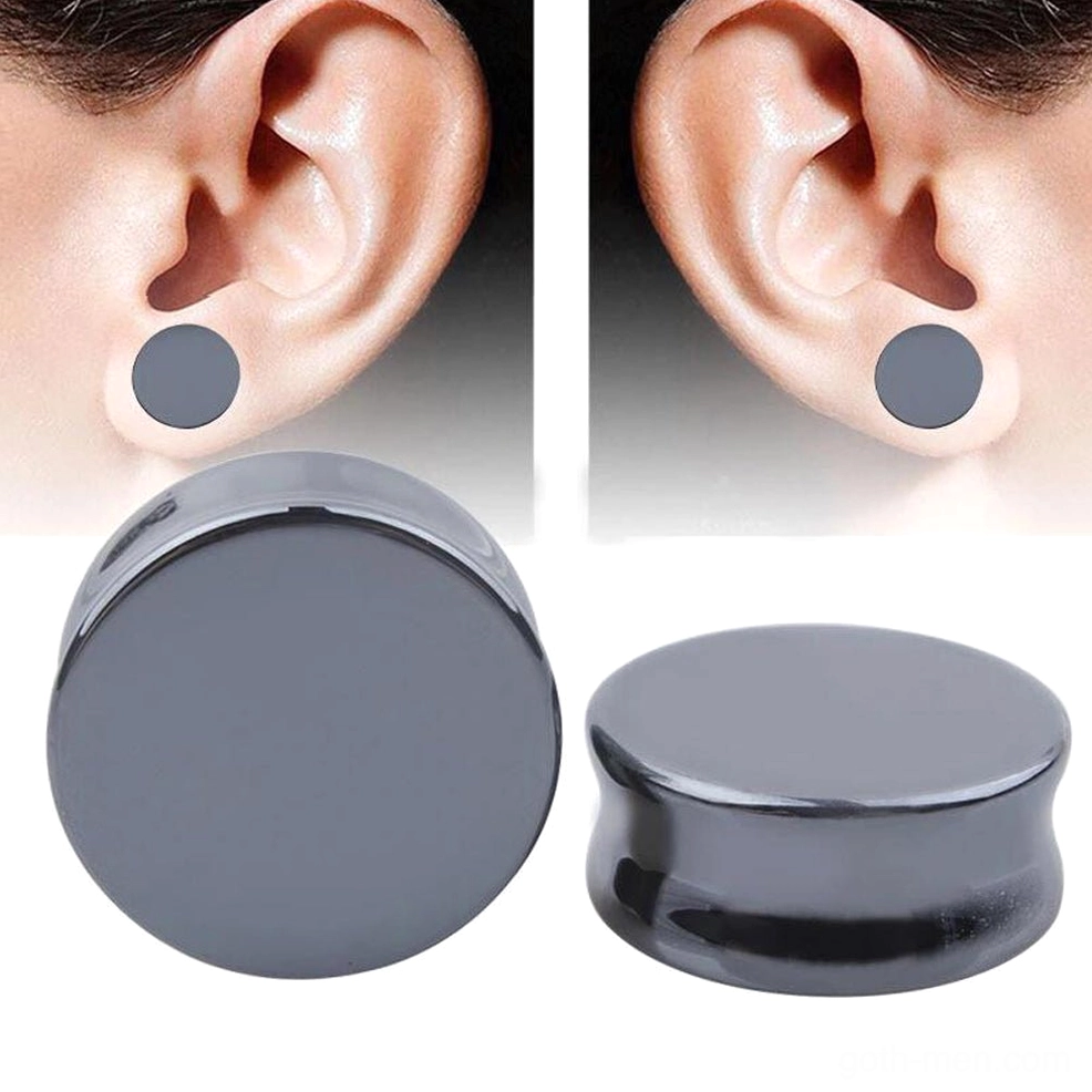 Scattered arrangement of dark gray hematite stone ear plugs displaying various sizes and double-flared cylindrical construction detail