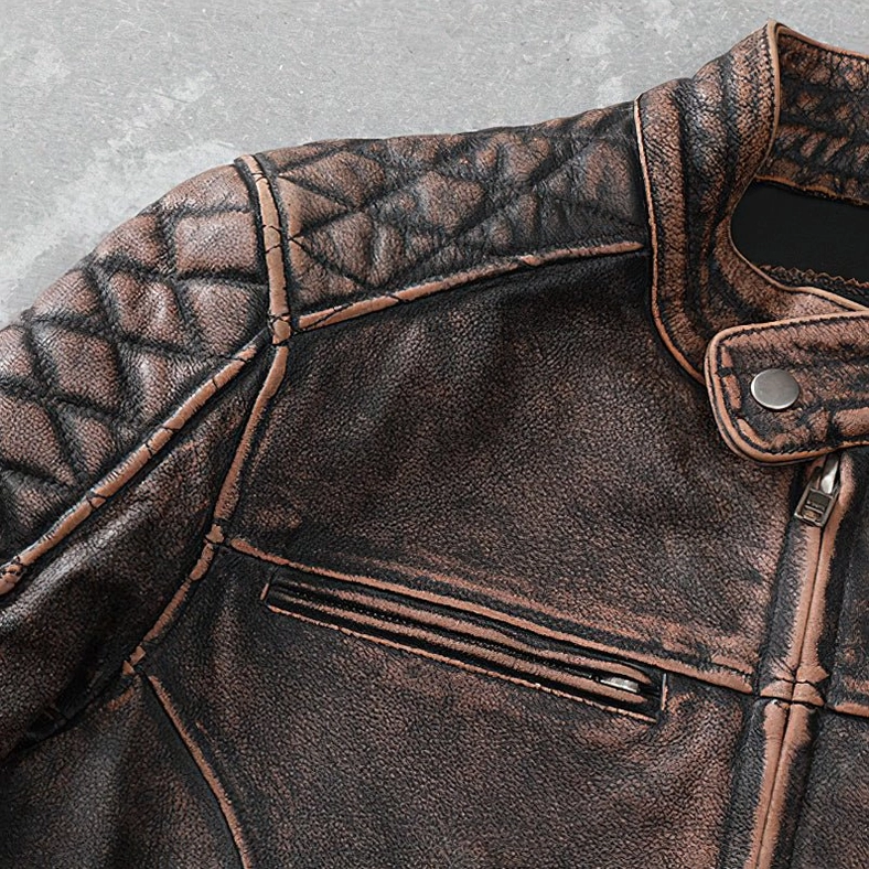 Close-up of gothic biker jacket shoulder showing diamond quilted stitching pattern and matte distressed leather finish