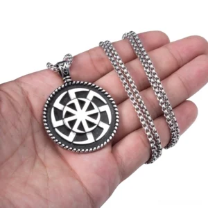 Kolovrat pagan sun symbol pendant held in human palm showing size and vintage stainless steel material detail