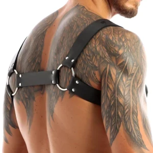 Black leather chest harness back view showing metal O-rings rivet straps and industrial design on shirtless male model