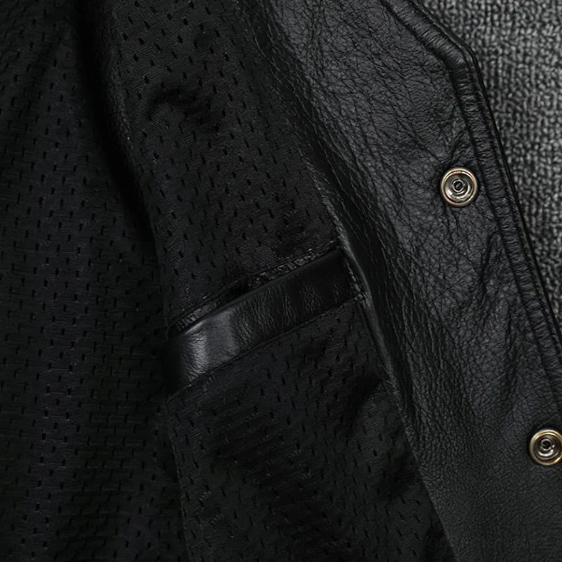 Close-up of inner pocket and metal snap buttons on black leather gothic vest, showing functional storage and hardware details