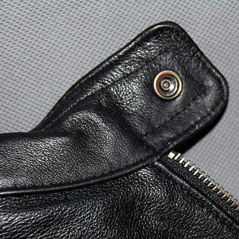 Genuine leather texture and metal hardware close-up showing zipper and snap fasteners on gothic biker jacket