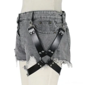 Gothic leg harness with black leather straps and metal buckle worn over frayed grey denim shorts, front view