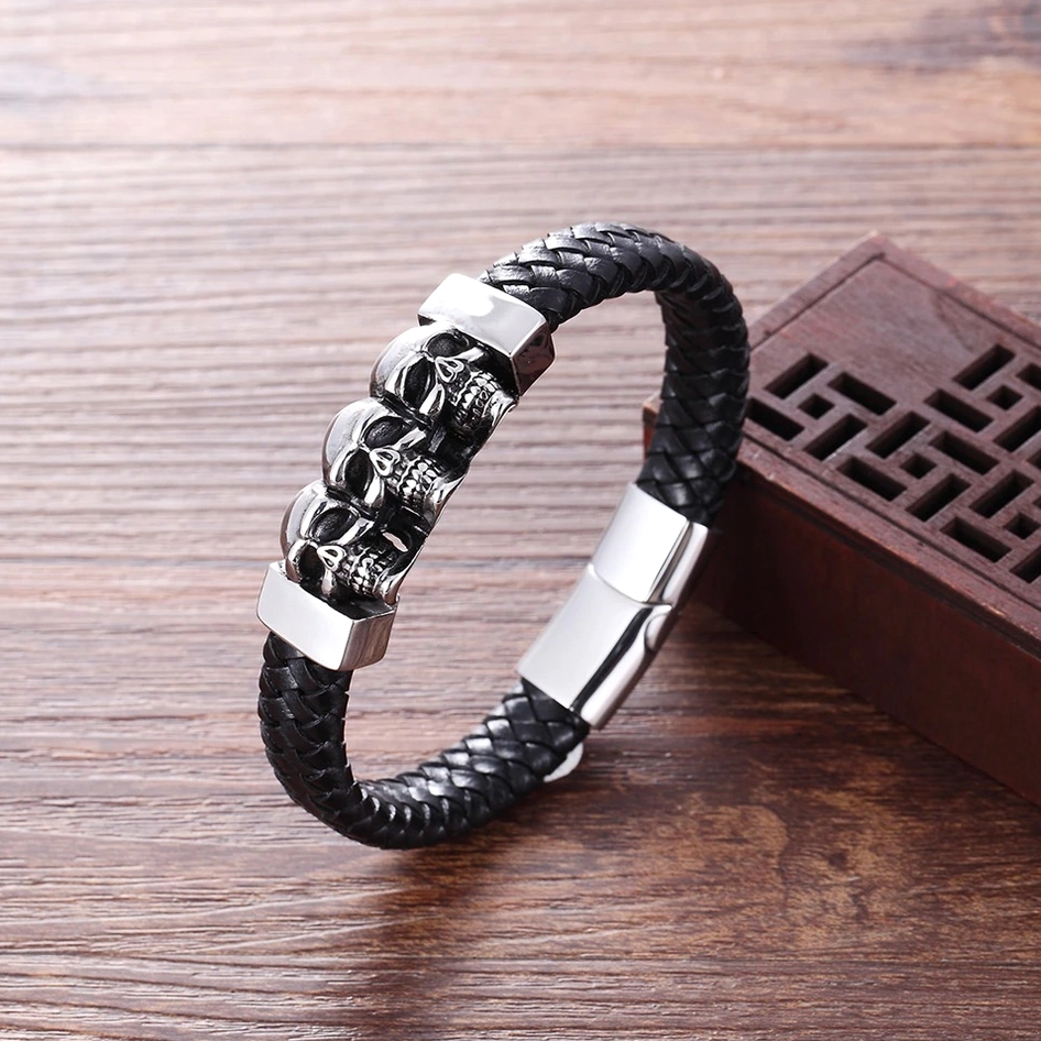 Gothic skull bracelet three-quarter angled view displaying braided leather texture and polished stainless steel hardware on wooden surface