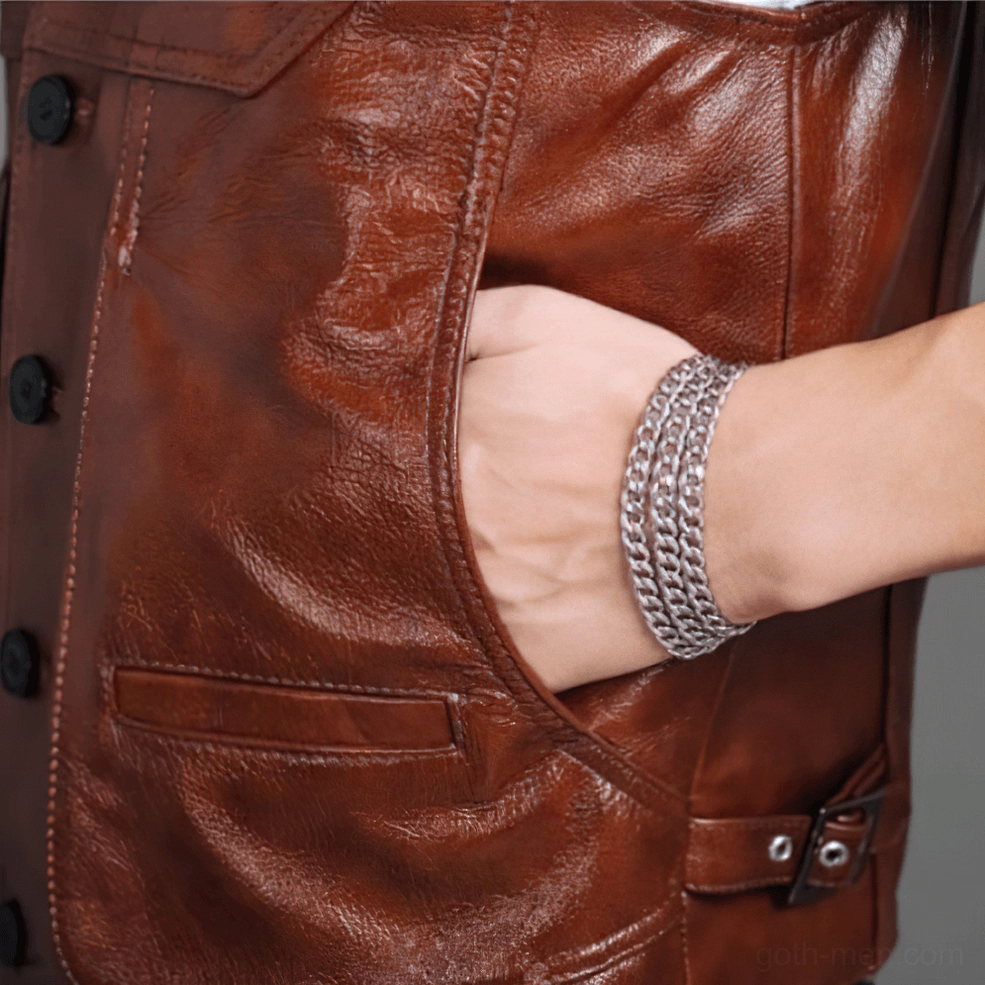 Side pocket detail of brown cowhide leather vest with male hand and silver chain bracelet showing natural leather texture