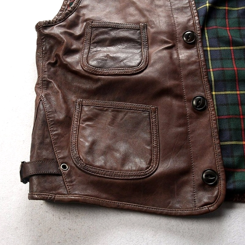 Close-up detail of reinforced stitched patch pocket and metal button fasteners on vintage brown leather waistcoat