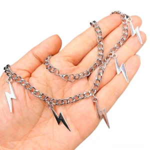 Close-up overhead view of silver and dark-toned lightning bolt chain pendant held in hand showing metallic curb chain detail