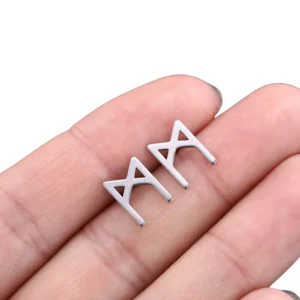 M-rune Viking stud earring in matte silver - gothic hollow design held between fingertips close-up