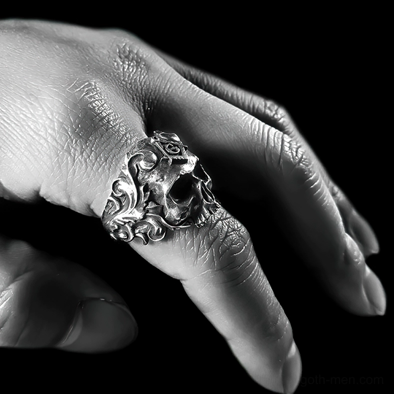 Close-up side view of masonic skull ring being worn highlighting floral engraving details in dark monochrome lighting