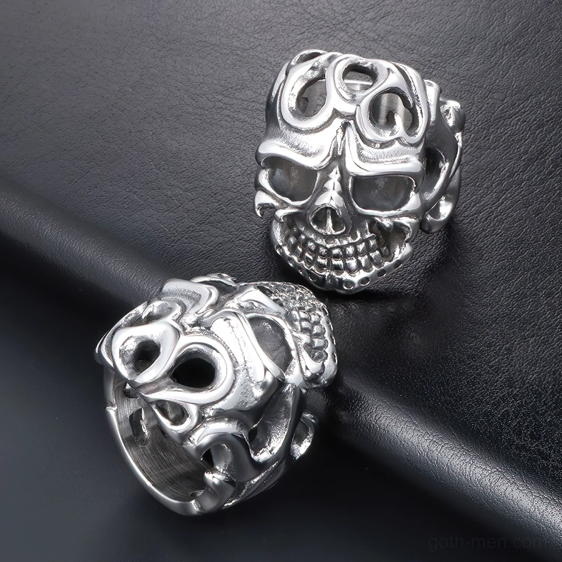 Two matching stainless steel skull rings with vintage hollow skull design overhead view on black leather surface