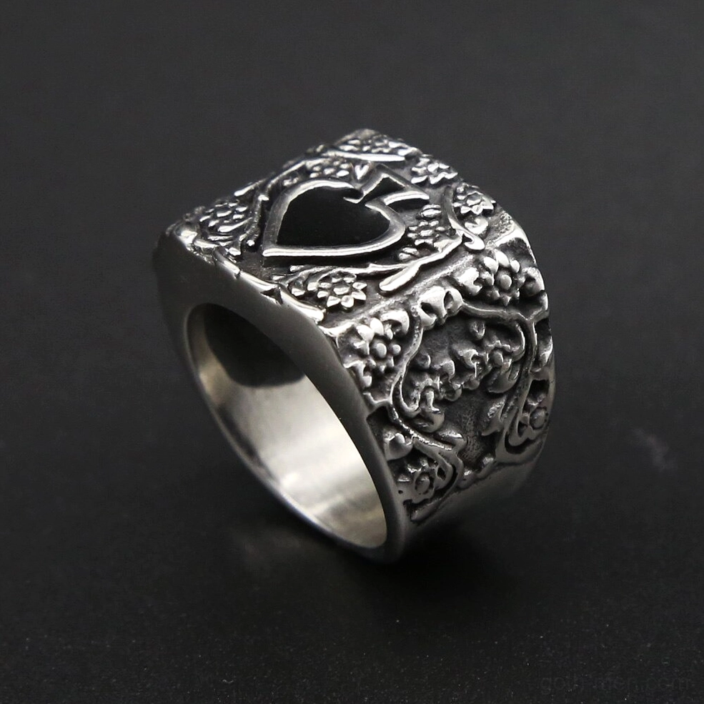Wide silver spade men's ring with floral engraved sides, angled side view on dark grey background showcasing band width