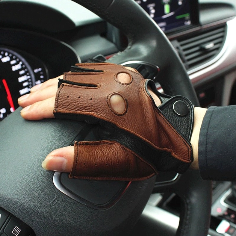 Brown fingerless driving gloves worn on male hand gripping car steering wheel in vehicle cockpit