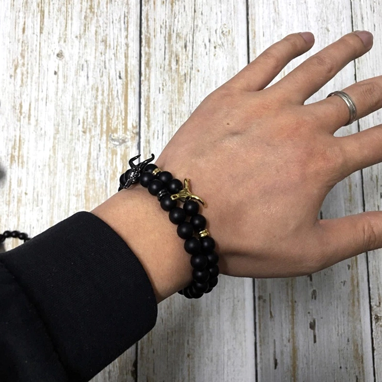 Man wearing gothic black stone bull charm beaded bracelet with gold accents, on-wrist styling demonstration