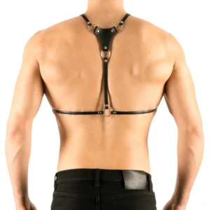 Black leather gothic harness back view showing adjustable straps, D-rings, and metal hardware on male model wearing dark pants