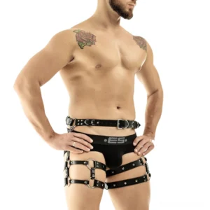 Shirtless male model wearing adjustable black gothic leather body harness with studded straps and branded underwear, three-quarter side view