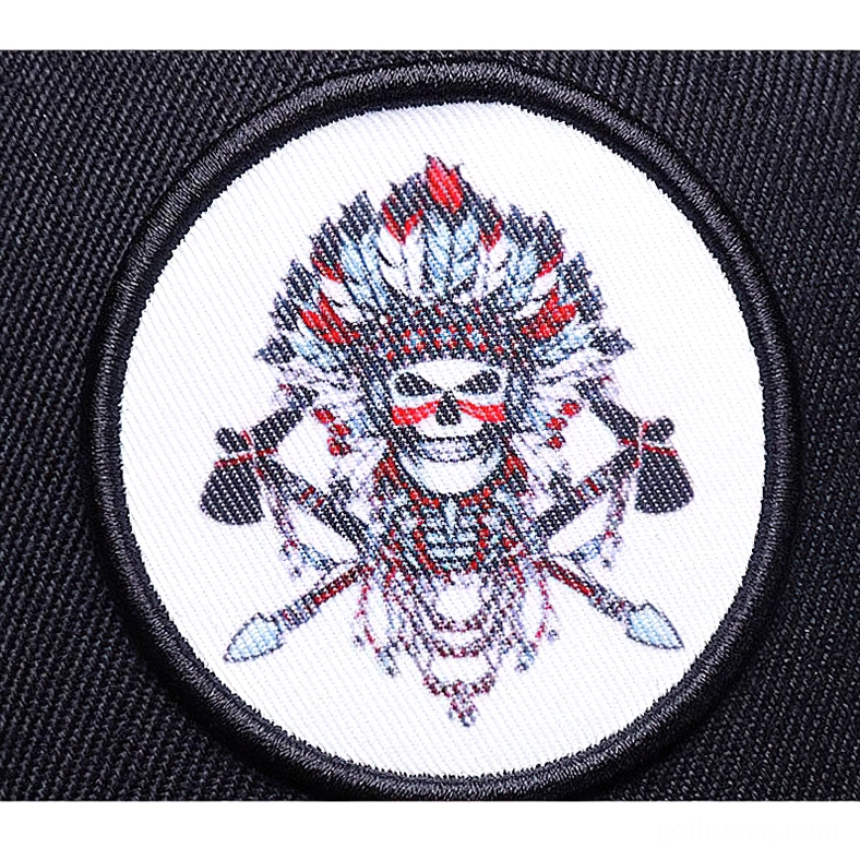 Detailed flat overhead close-up of intricate native skull embroidered patch featuring feather and weapon patterns gothic design elements
