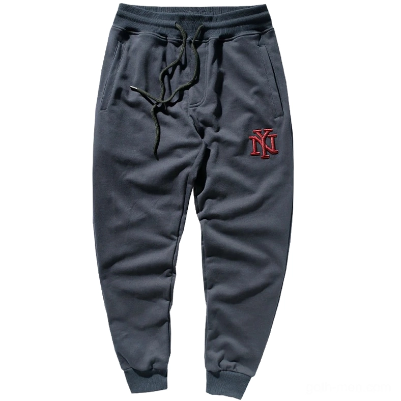 Dark navy blue embroidered jogger sweatpants with red NY logo, flat lay studio shot, gothic alternative style